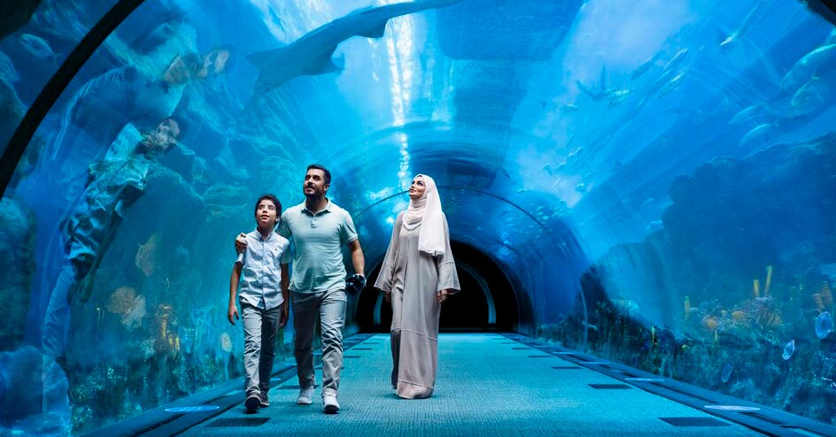 Family walking through the tunnel of the Aquarium with sharks swimming overhead