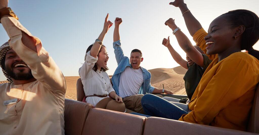 A group of friends celebrating in the back of a truck within the Dubai desert