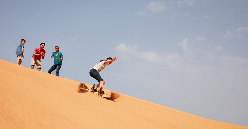 Family sandboarding in the Arabian Desert