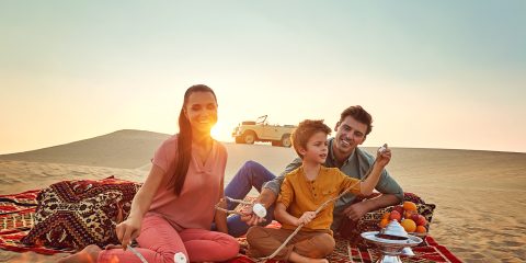 Family roasting marshmellows by a fire in Abu Dhabi desert