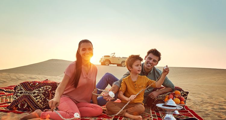 Family roasting marshmellows by a fire in Abu Dhabi desert