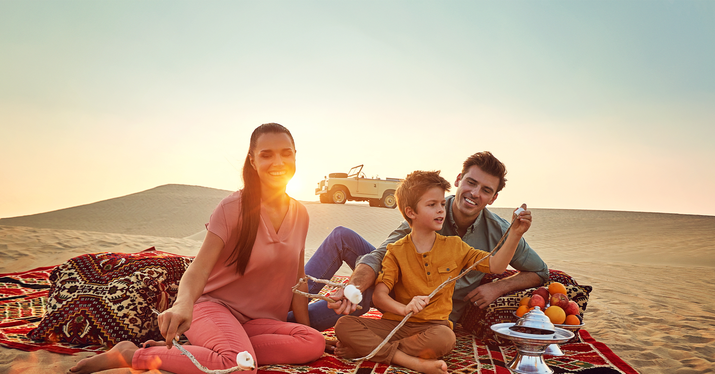 Family roasting marshmellows by a fire in Abu Dhabi desert