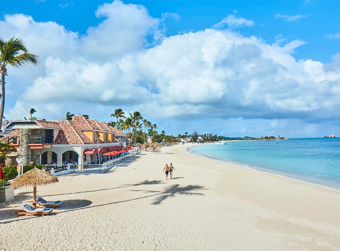 Couple walking on the beach at Sandals Grande Antigua