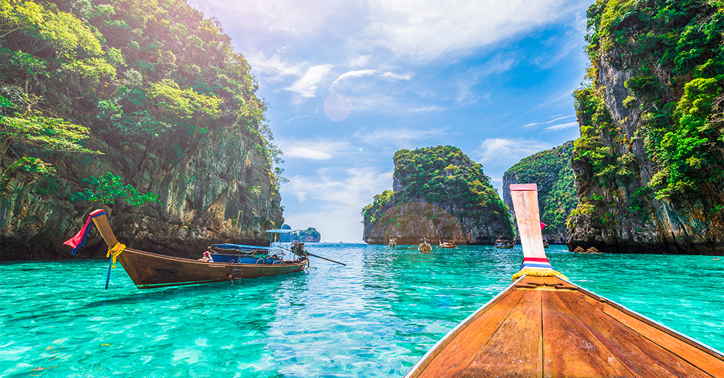 A classic view of Thailand's islands and crystal clear teal waters from the front of a longboat