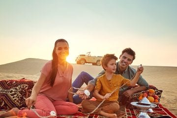 Family roasting marshmellows by a fire in Abu Dhabi desert