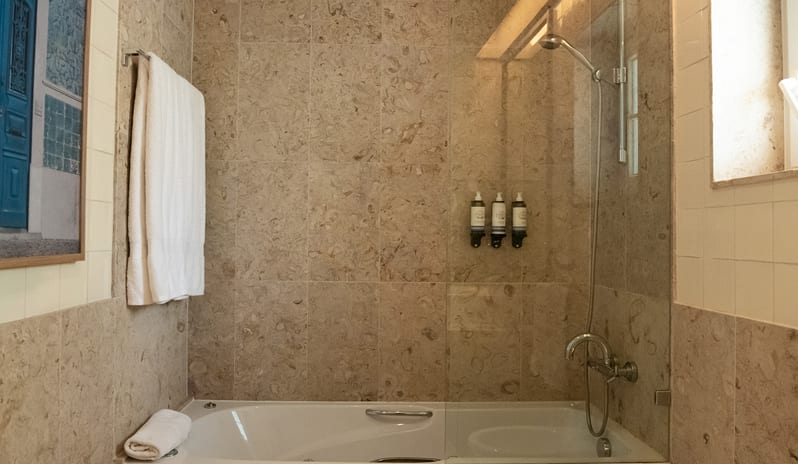 Elite Sapphire Two Bedroom Residence Spa-inspired bathroom with marble tiling and a deep soaking tub at Domes Lake Algarve by Kenwood Travel