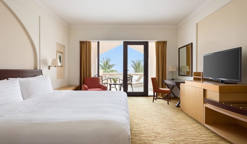 Guest Room with Sea View Bedroom featuring a king bed, private balcony with sea view, and contemporary Omani-inspired decor at Hilton Muscat Al Bandar by Kenwood Travel