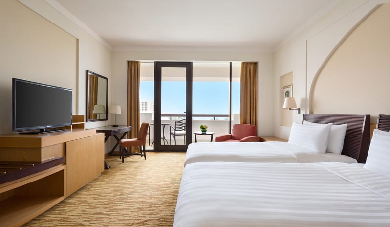 Guest Room with Sea View Bedroom featuring a king bed, private balcony with sea view, and contemporary Omani-inspired decor at Hilton Muscat Al Bandar by Kenwood Travel