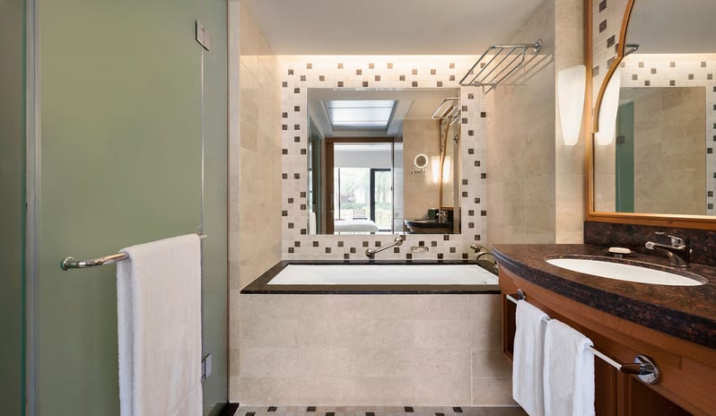 Guest Room with Terrace Bathroom with a large soaking tub, wood-finished vanity, and clean white towels at Hilton Muscat Al Bandar by Kenwood Travel