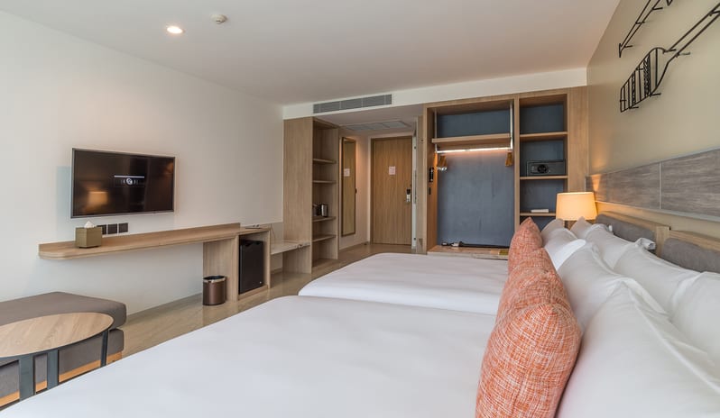 Deluxe Room featuring two twin beds with orange accent pillows, nautical oar wall art, a private balcony with sheer curtains, and a contemporary seating area at Centara Ao Nang Beach Resort & Spa Krabi by Kenwood Travel