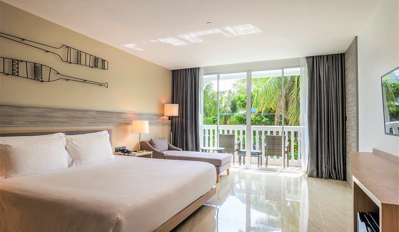 Premium Deluxe Room featuring a king bed, nautical wall art, and a private balcony with palm tree views. at Centara Ao Nang Beach Resort & Spa Krabi by Kenwood Travel