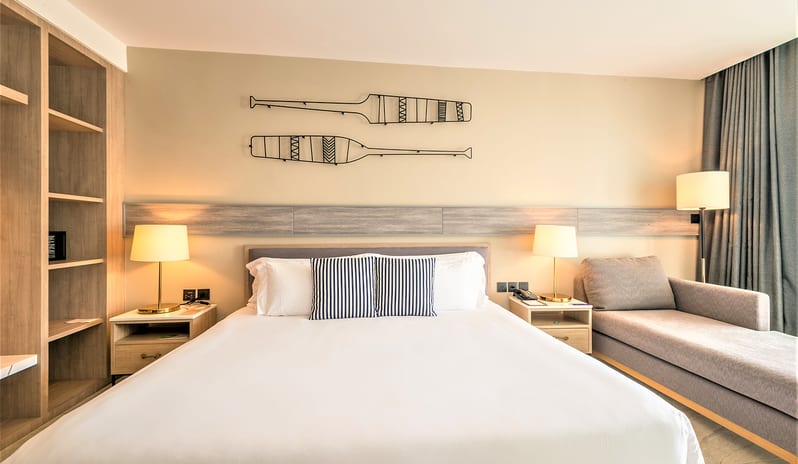 Premium Deluxe Room featuring a king bed with striped pillows, decorative wall oars, and a grey chaise lounge at Centara Ao Nang Beach Resort & Spa Krabi by Kenwood Travel
