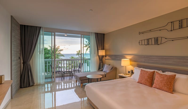 Deluxe Pool Access Room ocean view hotel suite featuring a king bed, wall-mounted TV, and private balcony overlooking the sea at sunset at Centara Ao Nang Beach Resort & Spa Krabi by Kenwood Travel