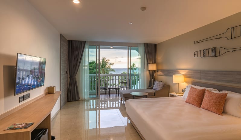 Deluxe Pool Access Room ocean view hotel suite featuring a king bed, wall-mounted TV, and private balcony overlooking the sea at sunset at Centara Ao Nang Beach Resort & Spa Krabi by Kenwood Travel