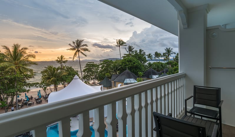 Deluxe Pool Access RoomTropical resort balcony view at sunset featuring outdoor seating, palm trees, and a beachfront pool area with white canopies at Centara Ao Nang Beach Resort & Spa Krabi by Kenwood Travel