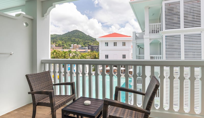 Premium Deluxe Pool Terrace Room Outdoor terrace seating at a luxury resort with views of a pool area and lush green hills under a blue sky at Centara Ao Nang Beach Resort & Spa Krabi by Kenwood Travel