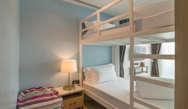 Minimalist white metal bunk beds in a family residence room featuring light blue walls, a bedside lamp, and a purple striped bean bag at Centara Ao Nang Beach Resort & Spa Krabi by Kenwood Travel