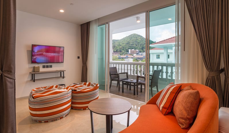 Family Residence Bedroom Luxury suite interior with a seating area, flat-screen TV, and sliding glass doors leading to a furnished balcony with mountain views at Centara Ao Nang Beach Resort & Spa Krabi by Kenwood Travel