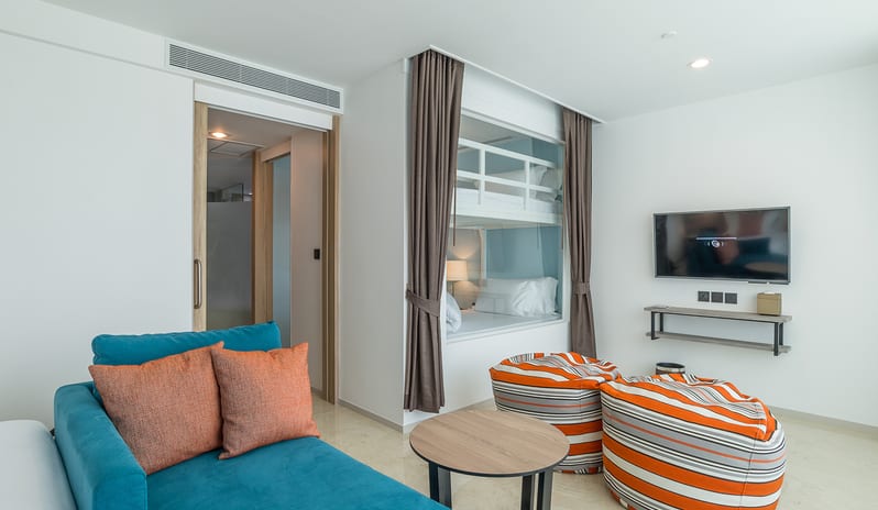 Family Residence Bedroom Modern living area in a family suite with a teal sofa, bean bags, and integrated bunk beds behind a glass partition at Centara Ao Nang Beach Resort & Spa Krabi by Kenwood Travel
