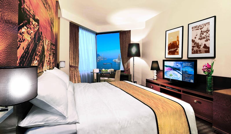 Grand Deluxe Harbourview Room with a view of Victoria Harbour, king-sized bed, and modern decor at Harbour Grand Hong Kong by Kenwood Travel