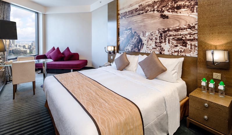 Grand Deluxe Harbourview Room King bed, a purple sofa bed, and a large window overlooking the city harbour at Harbour Grand Hong Kong by Kenwood Travel