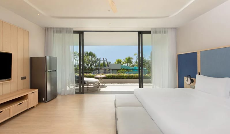 Family Pool View Suite sliding glass doors to a private balcony overlooking the resort's pool and water slide area at Anantara Koh Yao Yai Resort & Villas by Kenwood Travel