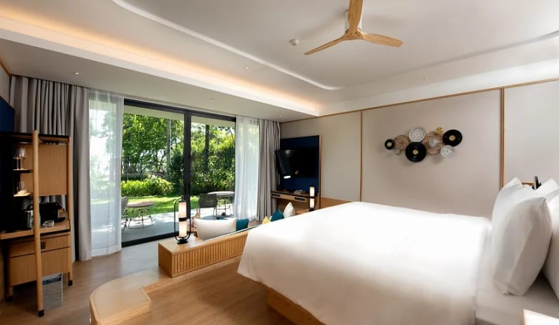 Deluxe Garden Access Suite elevated bed overlooking a private garden terrace through floor-to-ceiling glass doors at Anantara Koh Yao Yai Resort & Villas by Kenwood Travel