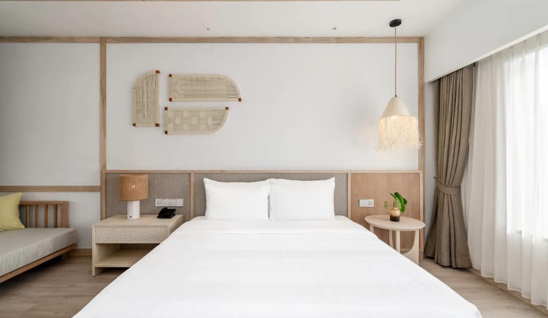 Deluxe Sea View Villa Bedroom King-size bed, vaulted wood-beam ceiling, and large windows overlooking a beach and palm trees at SAii Phi Phi Island Village by Kenwood Travel