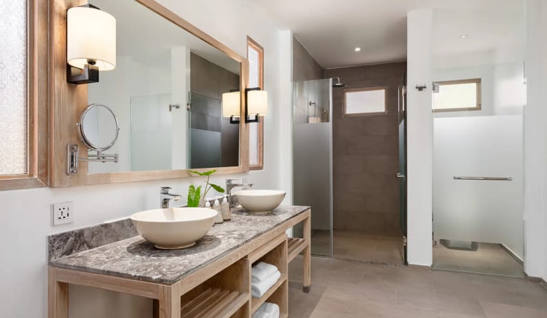 Deluxe Sea View Villa Modern luxury resort bathroom featuring a marble double vanity with vessel sinks, large wood-framed mirror, and a walk-in rainfall shower at SAii Phi Phi Island Village by Kenwood Travel