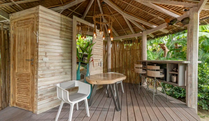 Beachfront Pool Villa Interior with Wooden Dining Area, Open-air Bar, Bamboo Decor, and Thatched Roof at TreeHouse Villas Koh Yao by Kenwood Travel