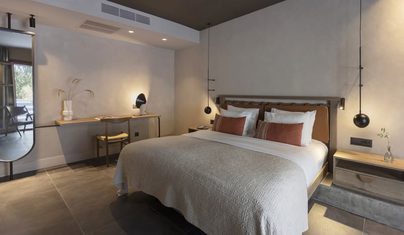 Tropical Bungalow Suite King-Sized Bed with Terracotta Pillows, Minimalist Hanging orb Lights, and a Built-in Wooden Desk Areaat Aulūs Lindos Rhodes, Curio Collection by Hilton by Kenwood Travel