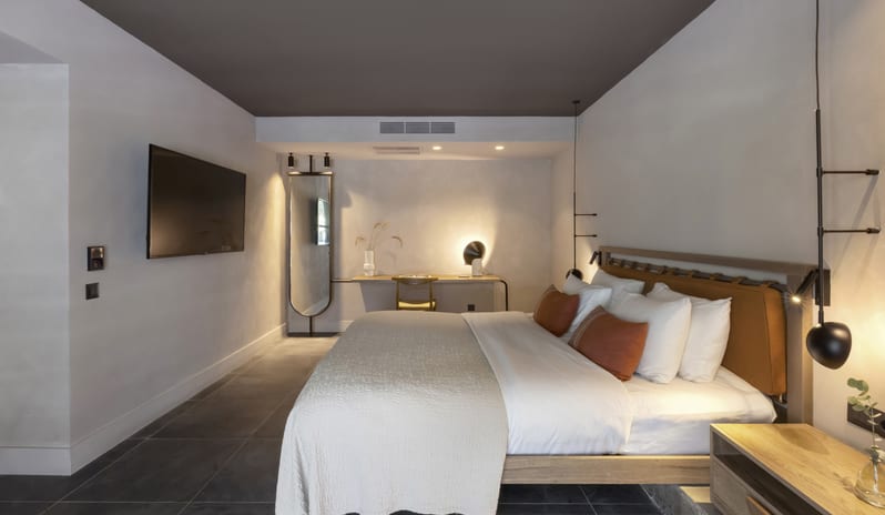 Tropical Bungalow Suite King-Sized Bed with Terracotta Pillows, Minimalist Hanging orb Lights, and a Built-in Wooden Desk Areaat Aulūs Lindos Rhodes, Curio Collection by Hilton by Kenwood Travel