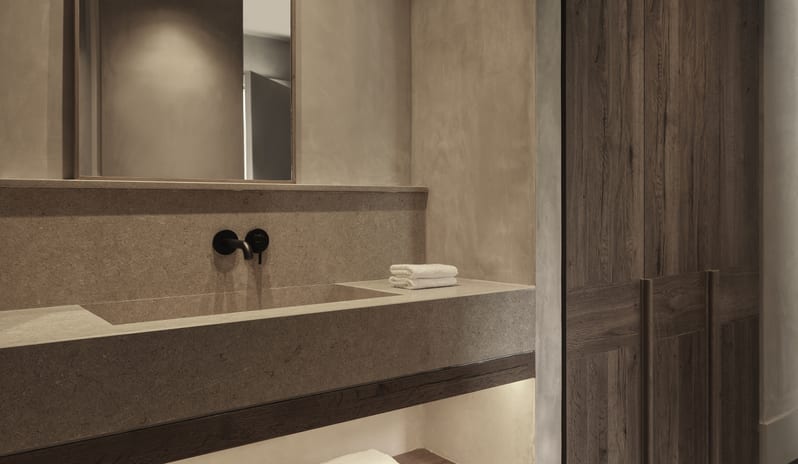 Tropical Cozy Retreat Modern Bathroom Interior Highlighting Soft Recessed Lighting on Textured Walls and Organised Wooden Storage at Aulūs Lindos Rhodes, Curio Collection by Hilton by Kenwood Travel