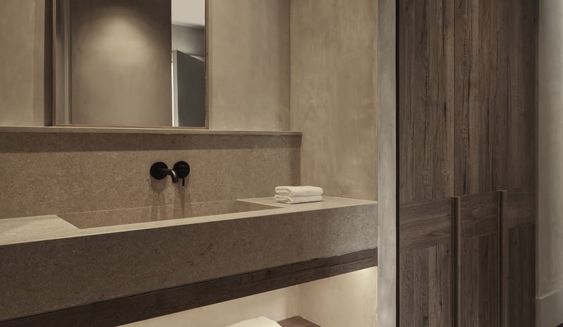 Tropical Retreat Upscale hotel bathroom interior with a serene tropical retreat aesthetic and organic earthy finishes at Aulūs Lindos Rhodes, Curio Collection by Hilton by Kenwood Travel