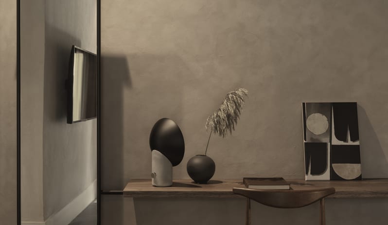 Tropical Retreat Desk Setup with a Wooden Wishbone-Style Chair, Designer Black Lamp, and Pampas Grass in a Vase against a Limewash Wall at Aulūs Lindos Rhodes, Curio Collection by Hilton by Kenwood Travel