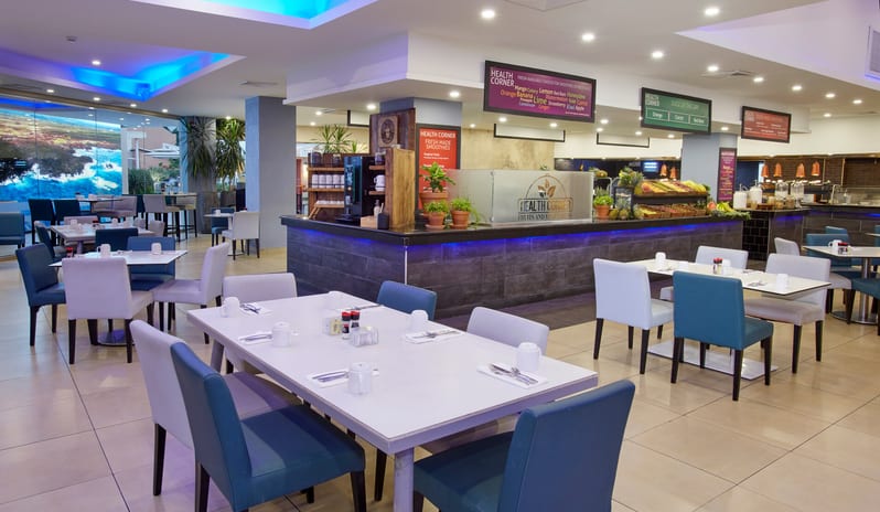 Cunucu Terrace Interior view of a buffet breakfast area in a resort, highlighted by blue neon accent lighting and a fruit bar at Divi Aruba All Inclusive Resort by Kenwood Travel