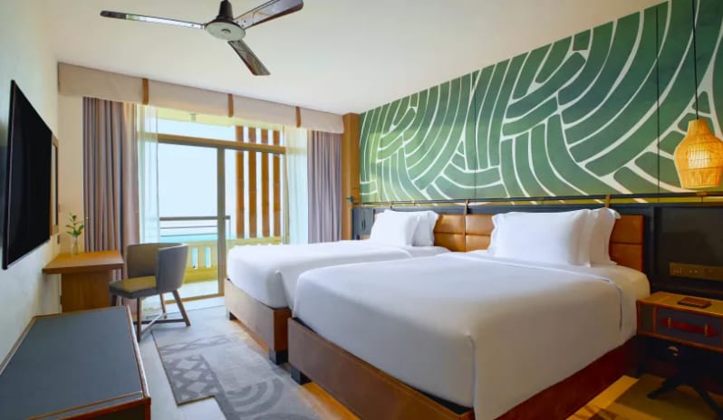 Mirage Suite (DBL/DBL) two double beds, a green patterned accent wall, and a view of the balconyat Centara Grand Mirage Beah Resort by Kenwood Travel