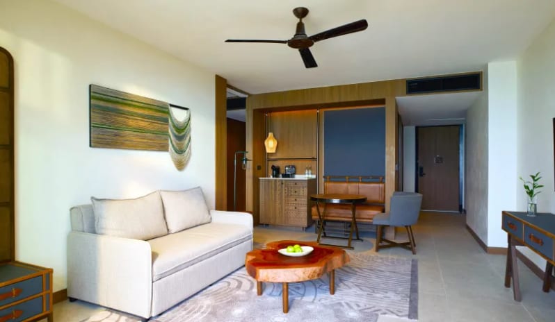 Mirage Suite (King)lounge featuring a live-edge wood coffee table, a sleek sofa, and a built-in dining nook with leather bench seating at Centara Grand Mirage Beah Resort by Kenwood Travel