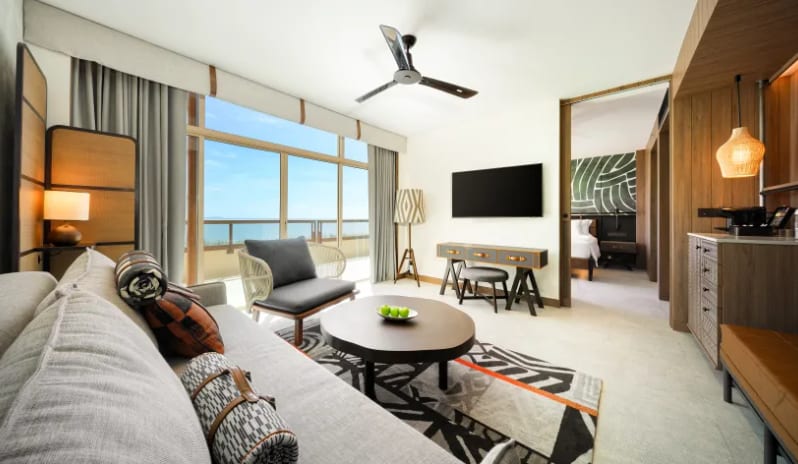 Mirage Suite (King)living room showing a kitchenette area with an espresso machine, leather bench seating, and a large wall-mounted TV at Centara Grand Mirage Beah Resort by Kenwood Travel