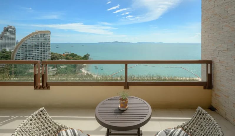 Mirage Suite (DBL/DBL) Private balcony of the Mirage Explorer Suite overlooking a tropical turquoise ocean, featuring two woven chairs and a small bistro table at Centara Grand Mirage Beah Resort by Kenwood Travel