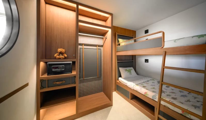Mirage Family Suite with Bunk Bed (DBL/DBL) wooden bunk beds with dinosaur-patterned bedding, a built-in closet with an integrated digital safe, and a small teddy bear on a shelf at Centara Grand Mirage Beah Resort by Kenwood Travel