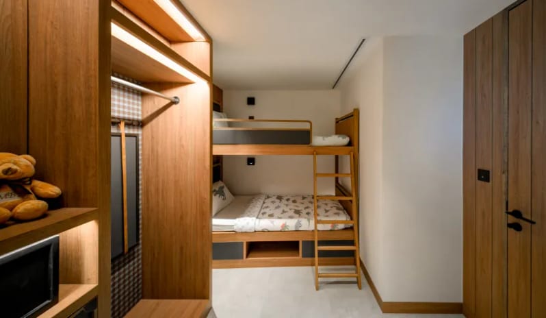 Mirage Family Suite with Bunk Bed (DBL/DBL) wooden bunk beds with dinosaur-patterned bedding, a built-in closet with an integrated digital safe, and a small teddy bear on a shelf at Centara Grand Mirage Beah Resort by Kenwood Travel