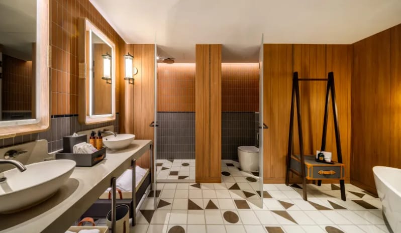 Mirage Family Suite with Bunk Bed (King) bathroom in the Mirage Family Expedition Suite featuring a double vanity with vessel sinks, a standalone soaking tub, geometric floor tiling, and wood-paneled walls at Centara Grand Mirage Beah Resort by Kenwood Travel