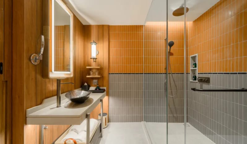 Premium Explorer (DBL/DBL) bathroom with orange and grey tiling, a walk-in glass rain shower, and a contemporary vanity with a backlit mirror at Centara Grand Mirage Beah Resort by Kenwood Travel