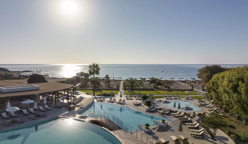 The Spiritzeria large turquoise swimming pool, a central domed gazebo bar, sun loungers, and scenic mountain views at Aulūs Lindos Rhodes, Curio Collection by Hilton by Kenwood Travel