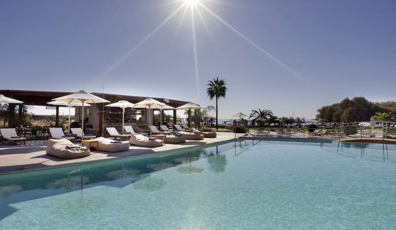 The Spiritzeria large turquoise swimming pool, a central domed gazebo bar, sun loungers, and scenic mountain views at Aulūs Lindos Rhodes, Curio Collection by Hilton by Kenwood Travel