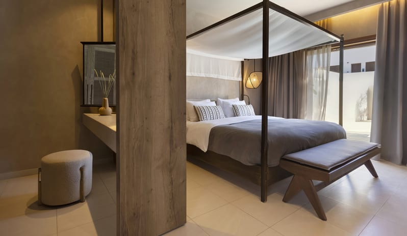 Tropical Bungalow Suite with Private Pool Bedroom Canopy Bed with White draping, dark wood furniture, a private vanity area, and neutral earth-toned decor at Aulūs Lindos Rhodes, Curio Collection by Hilton by Kenwood Travel