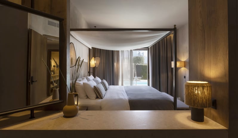 Tropical Bungalow Suite with Private Pool Bedroom Canopy Bed with White draping, dark wood furniture, a private vanity area, and neutral earth-toned decor at Aulūs Lindos Rhodes, Curio Collection by Hilton by Kenwood Travel
