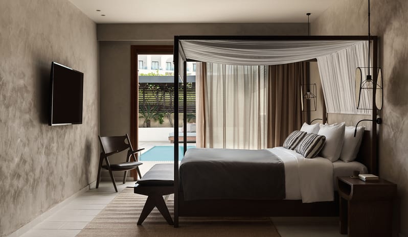 Tropical Pavilion One Bedroom Suite with Private Pool one-bedroom suite with textured plaster walls, a dark wood canopy bed at Aulūs Lindos Rhodes, Curio Collection by Hilton by Kenwood Travel