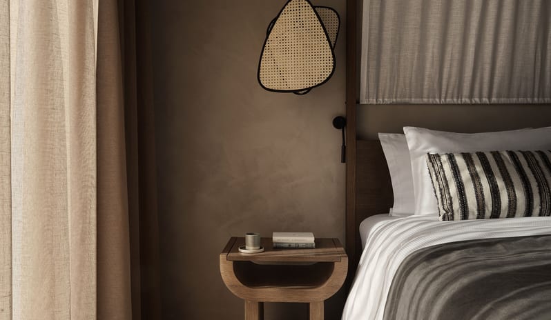 Tropical Pavilion One Bedroom Suite with Private Pool Close-up of a Pavilion suite bedside featuring a curved wooden nightstand at Aulūs Lindos Rhodes, Curio Collection by Hilton by Kenwood Travel